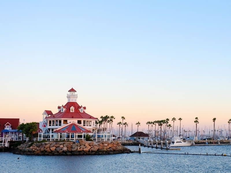 the beautiful harbor lighthouse with marina and palm trees at sunset colors