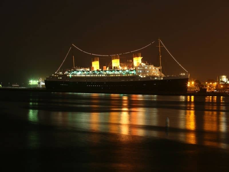 boat lit up with lights at night and water lit up as well