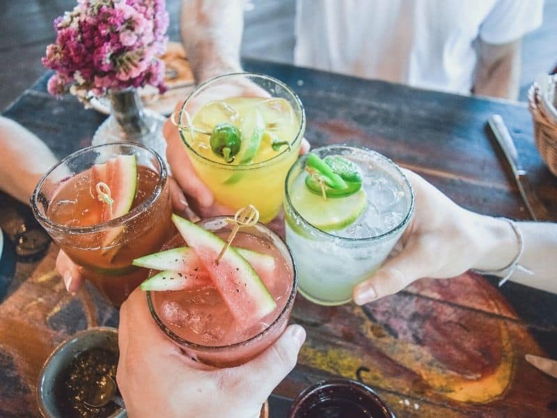 four hands cheerings with different flavored margaritas including lime and watermelon