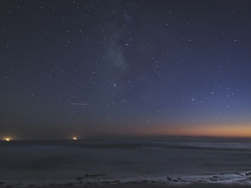 stars over the pacific ocean and lights from ships off the coast