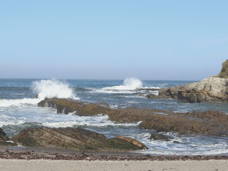 waves crashing on rocks in the ocean at spooners cove in Montana de oro state park near morro bay