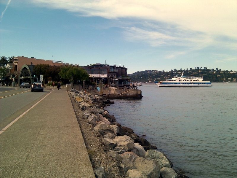 ferry arriving in sausalito from san francisco on the bay with houses in the distance visible