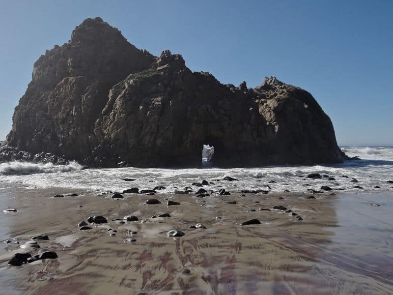 pfeiffer beach and rock formation with a small arch in it