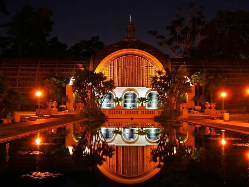 botanical garden building in bright red lights reflecting on a still pool at night