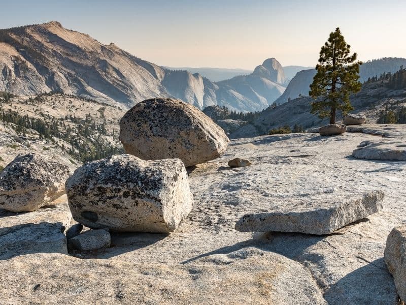 views close up of rocks along olmsted point with views of half dome and clouds rest in the distance