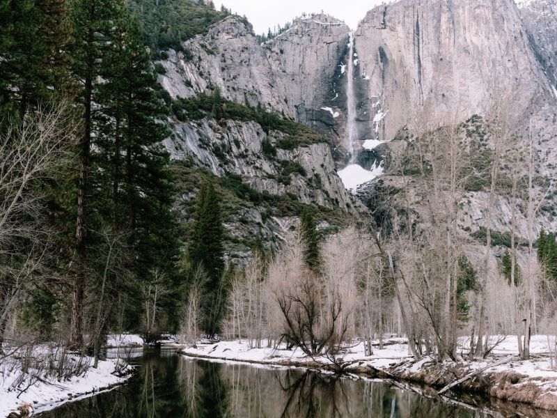 hiking in yosemite in winter with beautiful waterfalls and snow on the ground and a peaceful creek