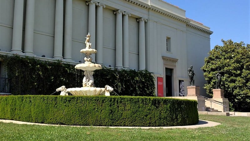 fountain, hedge, and white building with pillars at the huntingon library. andgardens