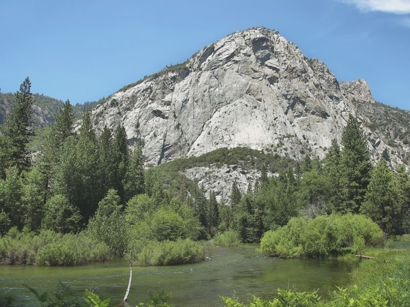 photo of a river surrounded by greenery and trees and a granite dome at kings canyon national park california