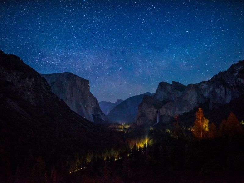 the night sky as seen from tunnel view with some lights visible and a waterfall in the distance