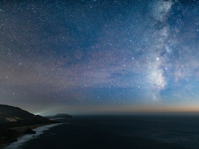 the brilliant milky way and colors on the horizon over the ocean on the pacific coast highway