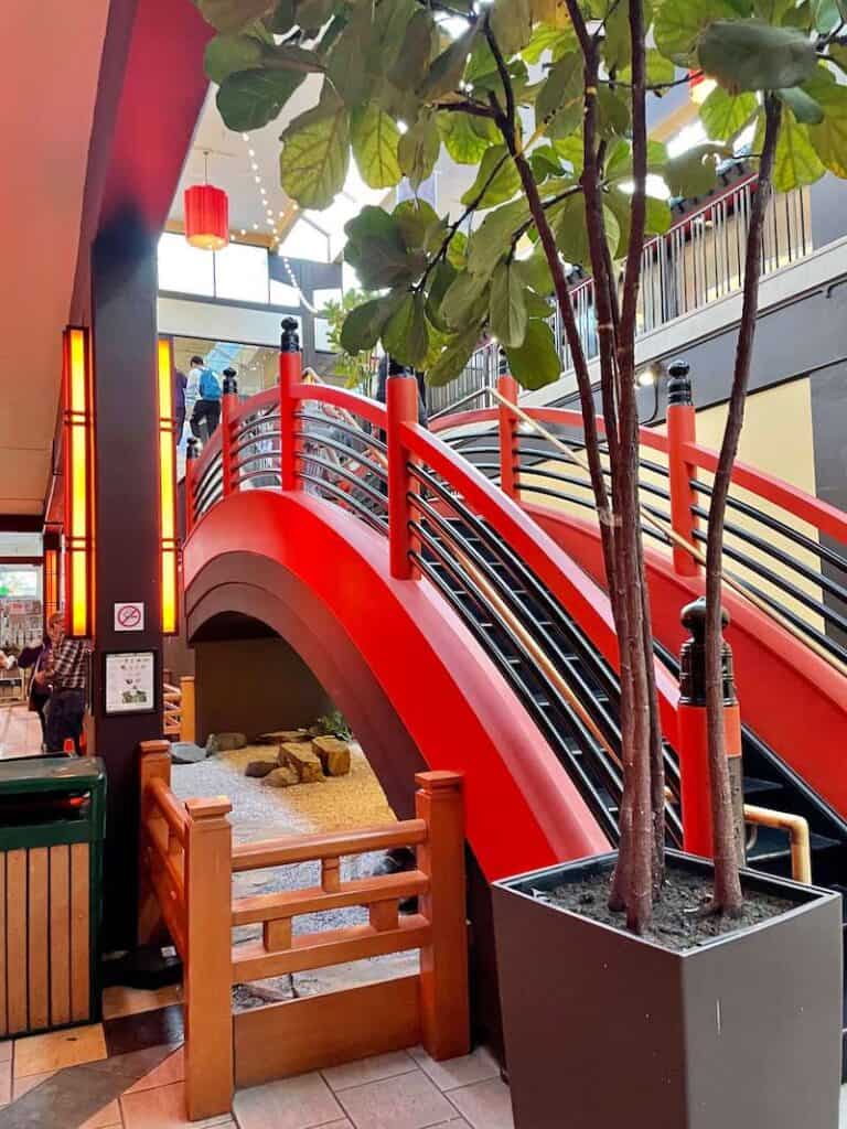 Fiddleleaf fig tree next to red bridge in an indoor mall