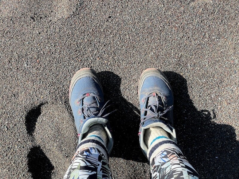 two feet in blue hiking boots with printed leggings on the black sand beach in sausalito