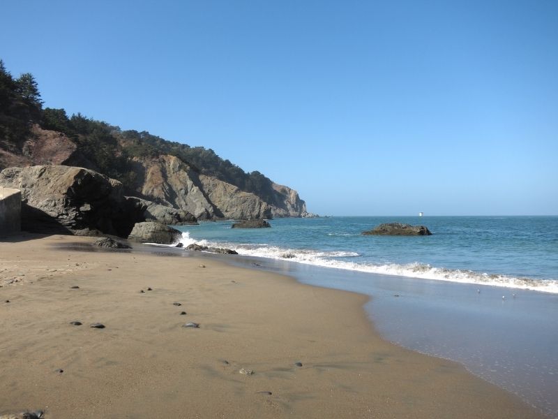 sandy shores of china beach with blue water and rocks in the background