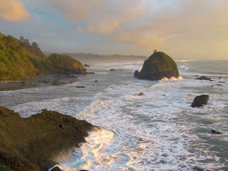 sunset colors washing over the rugged beach at houda point with a large round rock