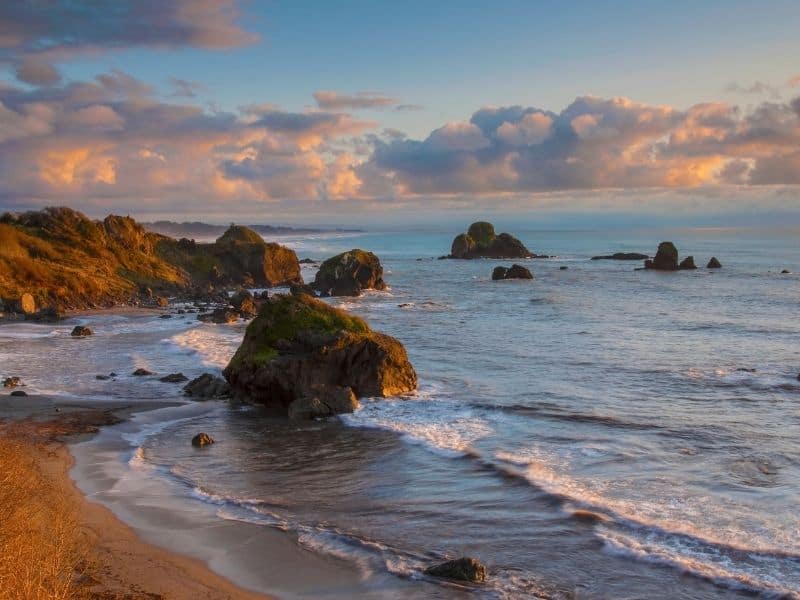 sandy beach with many large rock formations at sunset