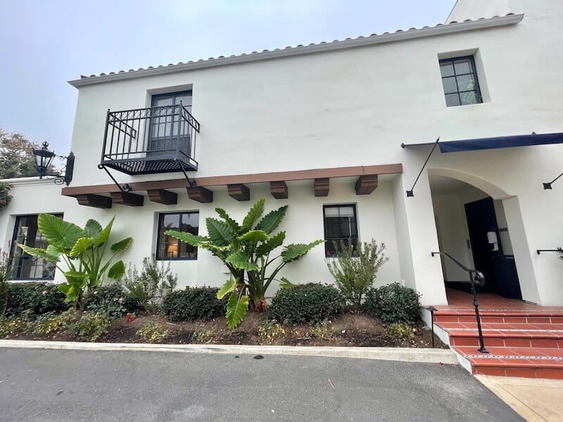 leafy green plant trees in front of a white Spanish colonial style building, a hotel in santa barbara