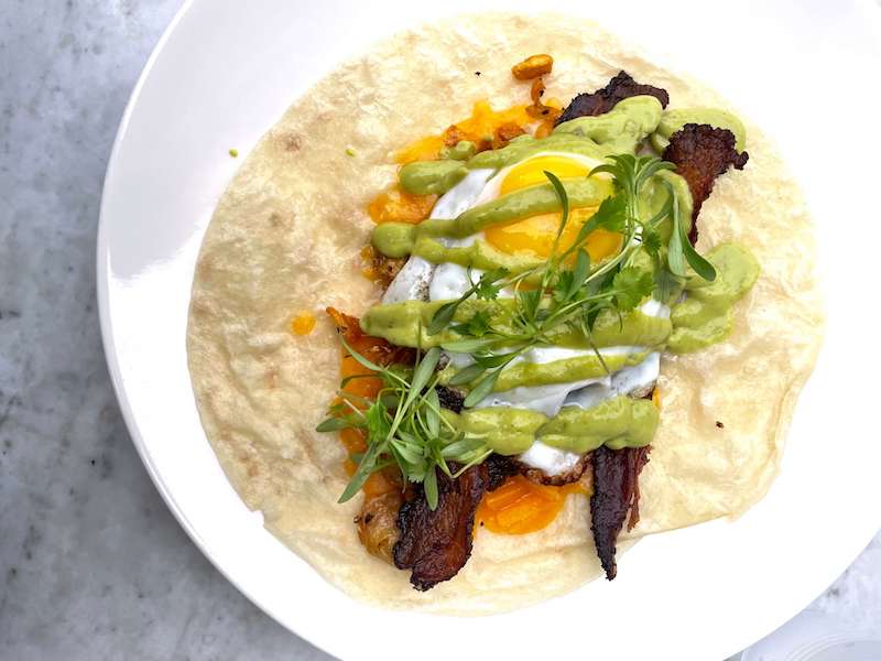 a breakfast taco with egg, salsa verde and bacon and greens