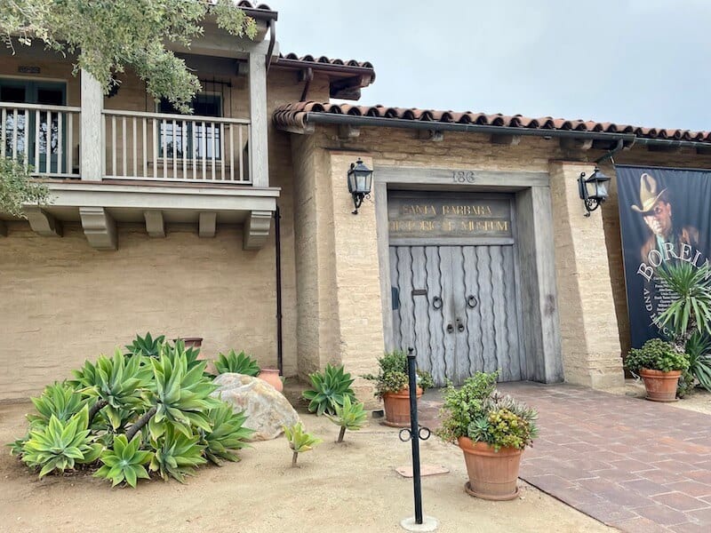 closed gate that reads santa barbara historical museum with yucca and other cactus in front