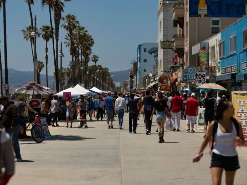 people walking on the boardwalk in venice becah california on a busy daay
