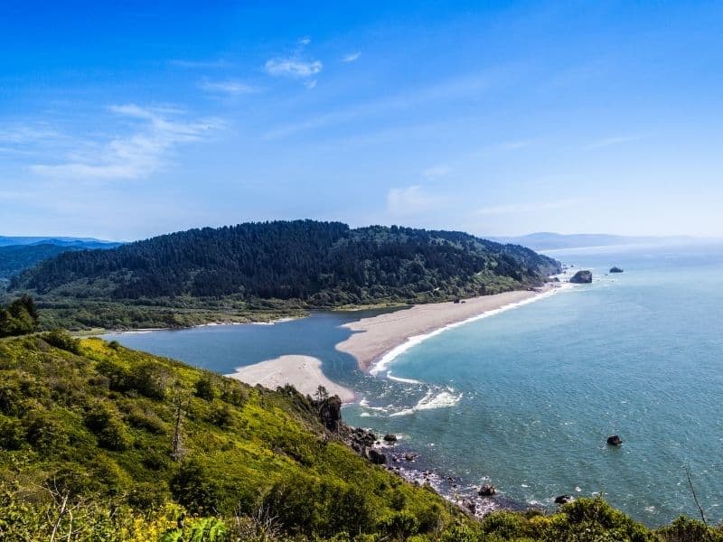 view of the klamath river emptying out into the pacific ocean on a blue sky day in redwoods national park