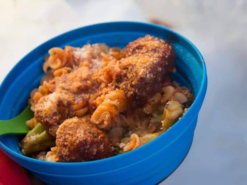 a bowl of pasta and meatballs in a blue bowl with a camp spork