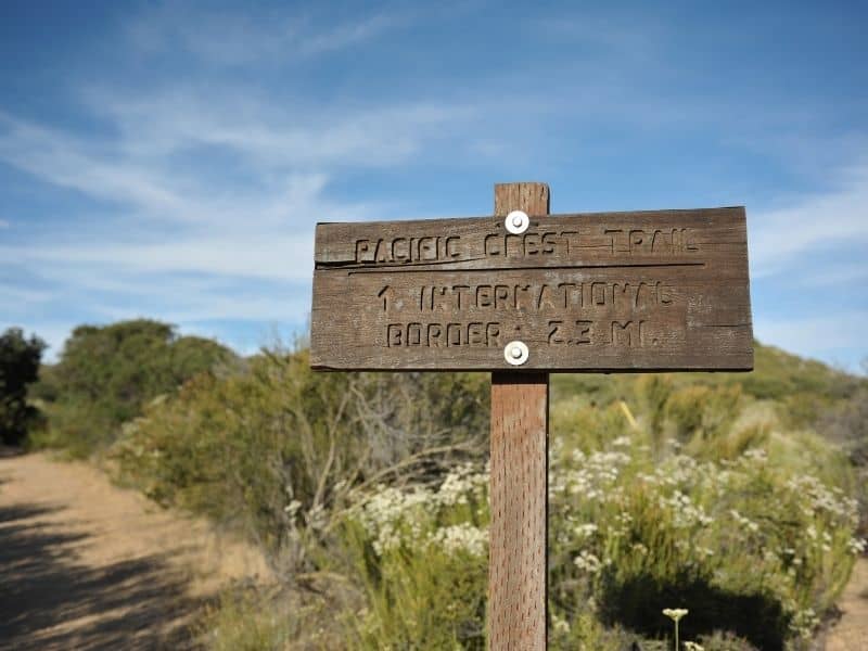 A sign that reads pacific crest trail with an arrow that says international border 2.3 miles on the way to the Mexican border, the end of the PCT