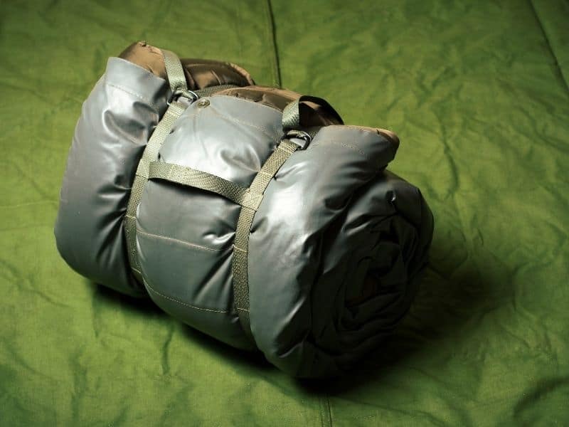 a green rolled up sleeping bag