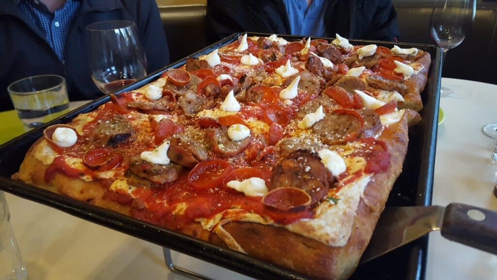A large rectangular pizza with tomato, cheese and meat